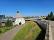 Building with a clock tower and a green hill in the background. There are people walking on the path in Kazan Kremlin Tatarstan
