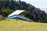 Soaring heights with gliders in vibrant blue and white fabric ready to take off from a grassy mountain launch point on a sunny day with a forest backdrop