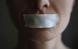 © VISTA by Westend61 - Person with adhesive tape on mouth representing censorship and silence