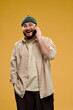 © VISTA by Westend61 - Smiling man wearing a beanie and glasses talking on the phone in a studio portrait