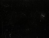 Grungy black surface with numerous white scratches and dust particles, creating a distressed and textured overlay for abstract or vintage designs.
