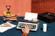 © VISTA by Westend61 - Hand typing on a mechanical typewriter with coffee and hourglass on a vintage style desk