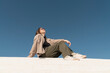 © VISTA by Westend61 - Woman sitting on steps outdoors under a clear blue sky, looking relaxed and fashionable
