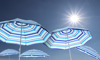 Wall Mural - bright striped beach umbrellas against blue sky on sunny day