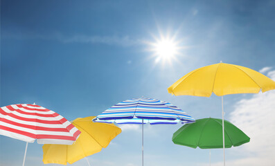 Wall Mural - different bright beach umbrellas against blue sky on sunny day