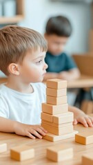 Poster - Young boy carefully placing wooden blocks on top of each other, building a tower during playtime in preschool, developing fine motor skills and concentration