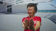 © Krakenimages.com - Senior woman with grey hair in red shirt gesturing stop at seaside promenade during daylight, showing rejection with a peaceful ocean backdrop and shadows cast on the ground.
