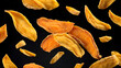 © Drago Designer - Close up of dried mango slices showing their texture and vibrant colors isolated against a black background