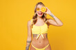 © ViDi Studio - Young beautiful sexy woman wears bikini swimsuit rest near hotel pool hold in hand cover eye with half of orange look camera isolated on plain yellow background. Summer vacation sea sun tan concept.