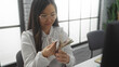 © Krakenimages.com - Woman counting chinese currency indoors, suggesting a professional office environment with a focus on finance and business activities within a modern workplace setting.