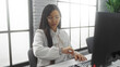 © Krakenimages.com - Woman checking watch in modern office wearing glasses next to computer showcasing focused work environment and stylish attire.