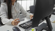 © Krakenimages.com - Woman holding credit card typing on keyboard in modern office setting showcasing a professional business environment.
