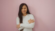 © Krakenimages.com - Woman with crossed arms stands against a pink background, looking thoughtful and confident, embodying youthful charm and beauty, isolated in a studio setting.
