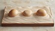 © sablengjago - Three smooth stones arranged on a wooden tray filled with wavy sand, creating a serene zen garden scene.