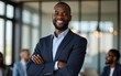 © li - Smiling confident african businessman looking at camera and standing in an office at team meeting smiling adult businesswear. High quality