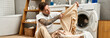 © LIGHTFIELD STUDIOS - Young handsome tattooed man engages in laundry chores at his cozy home while relaxing