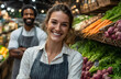 © Prasanth - Smiling woman in apron stands at grocery store aisle. Fresh food on shelves behind. Smiling staff member poses looking at camera. Supermarket shopping concept.