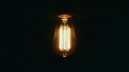 Poster - Close-up view of a glowing light bulb with a warm orange filament against a dark background enhancing its radiant illumination. The focus is sharp on the bulb details
