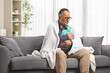 © Ljupco Smokovski - Sick mature man wrapped in blanket sitting on a sofa