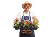 Man with an apron and straw hat holding a tray with flower pots
