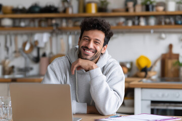 Poster - A man is smiling and sitting at a table with a laptop