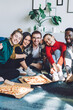 © BullRun - Multiethnic friends with pizza and to go drink at home party