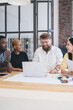 © BullRun - Contemporary positive multiethnic coworkers using laptop at office