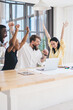 © BullRun - Excited multiethnic coworkers celebrating success while using laptop at office