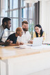 © BullRun - Group of concentrated multiethnic coworkers using laptop at office