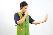 © Restu - Asian parking attendant wearing green vest blowing whistle while giving stop sign
