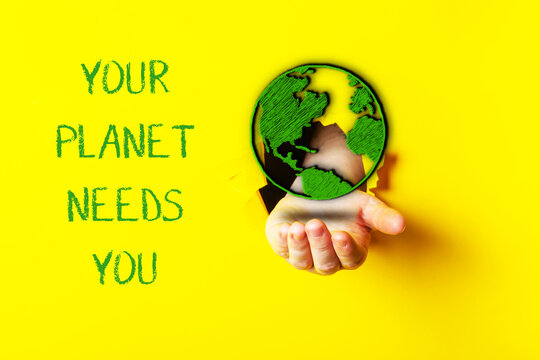 Hand holding a globe with the words Your planet needs you written below it