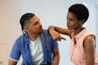 © Wavebreak Media - Talking couple pointing to chest while sitting in bright white home kitchen, natural light