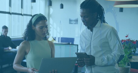 Poster - Collaborating coworkers reviewing laptop and smartphone in office with glass partitions, lights