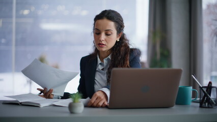 Poster - Confident businesswoman managing paperwork reviewing documents at laptop closeup