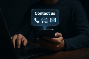 Fototapete - Person using phone with contact us bubble showing phone chat and email icons in dark setting