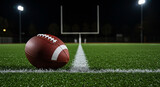 American football on the field at night with goal post and stadium lights in the background view at ground level