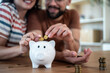 © Migma_Agency - Happy couple saving money together in piggy bank