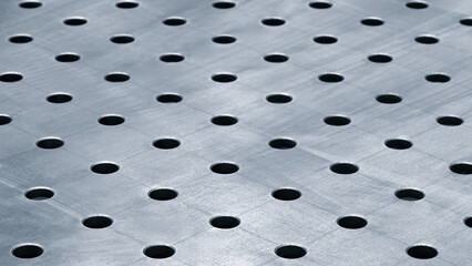 Poster - A close up of blue metal surface with many small holes. holes are evenly spaced and surface is shiny. Concept of precision and order, as well as a sense of emptiness or lack of substance