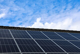 Photovoltaic panels capturing sunlight on a rooftop under a cloudy blue sky Photovoltaic panels capturing sunlight on a rooftop under a cloudy blue sky