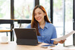 © David - Asian female successful employee business freelance is holding document to reading business data and financial chart while working with laptop in the workplace office.