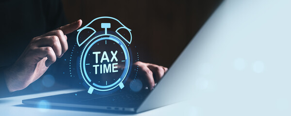 Poster - Hand pointing at glowing tax time icon on screen above laptop, emphasizing urgency of filing taxes with digital concept on dark background.
