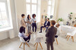 © Studio Romantic - Group of diverse business people chatting on meeting standing in circle in office. Company employees discussing work project. Coworkers listen to their colleague. Corporate business team concept.