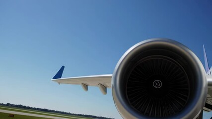 Poster - Powerful jet airplane engine and winglet gradually approaching camera on airport tarmac, revealing intricate mechanical details against pristine blue sky backdrop