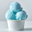 © Uttara Graphic - Three scoops of bright blue ice cream in a white paper cup isolated on white background