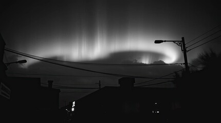 Wall Mural - Moody, low-contrast black and white street photograph depicting a candid view of the aurora borealis over an urban scene, emphasizing spontaneous moments