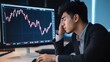 © widyastudio07 - Stressed asian businessman looking at falling stock market chart on computer