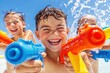 © Oleksandr Umanskyi - Boy and girl with water guns chasing each other near waterâ€™s edge, energetic summer play