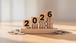 © Pixels Stock - Wooden blocks with numbers 2026 stacked on coins representing financial growth and success in the new year
