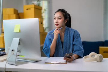Aufkleber - Young entrepreneur planning new marketing strategy using computer and smartphone in her home office