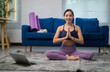 © PaeGAG - Asian sportswoman practicing yoga online following instructions on her laptop